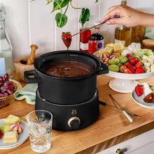Black electric fondue pot with melted chocolate and base temperature control dial