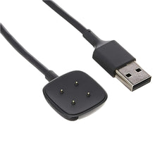 Black charging puck with prongs and USB-A cable connector, close-up.