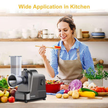 Electric cheese grater on countertop with transparent feed tube beside fresh vegetables.