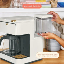 White coffee maker with removable water tank lifted by hand