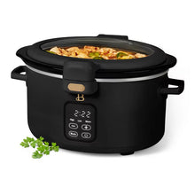 Black digital slow cooker with a hinged glass lid, front controls, and food visible inside