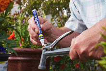 Hand uses precision pen lubricant to oil garden tool blades with the white nozzle