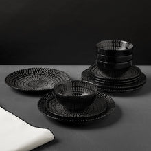 Stoneware dinnerware set with stack of black bowls and matching patterned plates