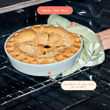 Light blue stoneware pie dish on oven rack holding baked pie
