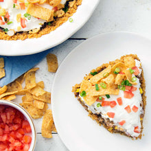 Bean dip topped with sour cream on chip crust, with diced tomato and green onions