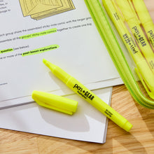 Yellow pocket highlighter markers with chisel tip, one cap off on notebook paper