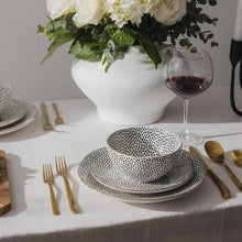 Stoneware tableware set with black dotted bowls and plates on dining table