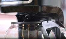 Glass carafe beneath brew head of a black drip coffee maker