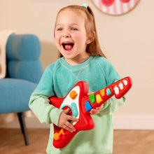 Red kid’s toy guitar with colored keys held by a laughing child