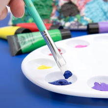 Paint brush with turquoise handle dipping into color on a white palette