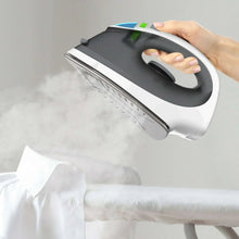 White and gray cordless steam iron steaming a folded white shirt
