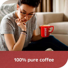 Nescafé instant coffee mug in a person’s hand, red mug with hot coffee