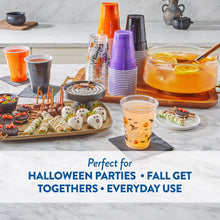 Orange-tinted Halloween cup with ghost, pumpkin, bat and skull print, alongside assorted color stacks.