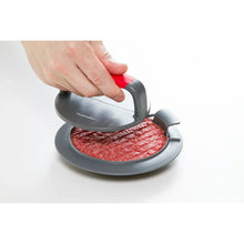 Hands using a burger press to stamp a raw patty on the base