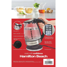 Electric glass kettle with black handle and control panel, held near the lid