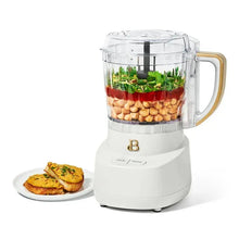 Drew Barrymore 3-cup food chopper with chopped ingredients in clear bowl and white base