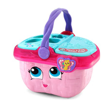Pink toy picnic basket with purple handle and teal activity panel, front view