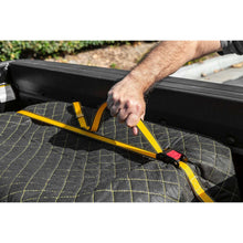 Ratchet tie-down strap being tightened across a cargo cover