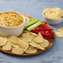 Potato chips with dip, celery sticks, and sliced vegetables on a platter