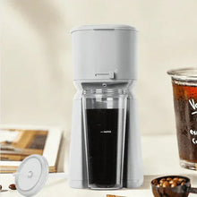 Soft silver single-serve iced coffee maker with open top and visible black brew tank