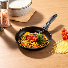 Black nonstick skillet with pasta and vegetables, short handle with rivets