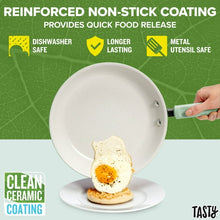 Sage green non-stick skillet with white interior and fried egg, shown being lifted by handle