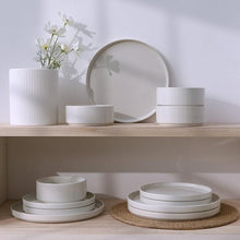 White stoneware dinnerware set with stacked plates and bowls on a shelf