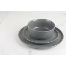 Matte gray stoneware bowl with matching plate and additional plates behind