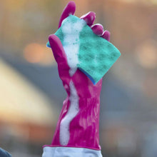 Magenta rubber cleaning glove holding a green sponge with suds