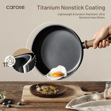 Black nonstick saute pan with wooden handle, showing an egg frying inside