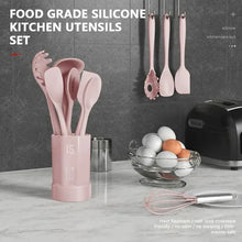 Pink silicone utensil set in holder with ladle, whisk, and spatulas