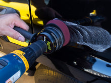 Rotary buffer polishing a dark car door with a maroon foam pad