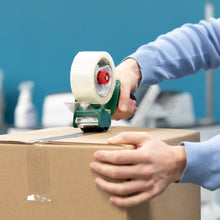 Hands sealing cardboard box with clear tape using tape dispenser