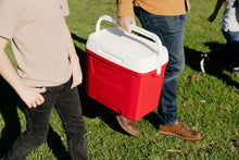 Red ice chest cooler with white lid being carried outdoors, side view