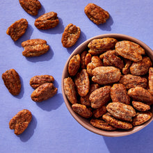 Praline pecans in a bowl with scattered pieces around