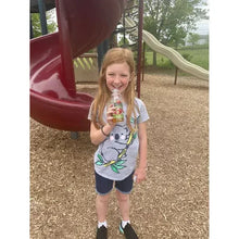 Child holding Apple & Eve apple juice bottle outdoors, label facing forward
