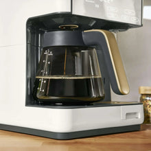Close-up of dark coffee brewing inside glass carafe in white coffee maker