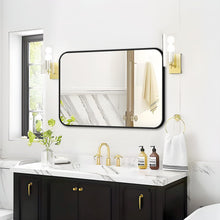 Bathroom mirror with black frame and rounded corners above a white sink vanity.