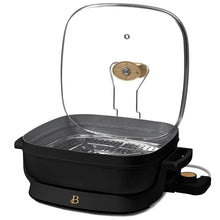Black electric skillet with raised stainless steam rack and glass lid