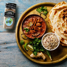 Garam masala seasoning blend jar beside curry bowl with rice and flatbread