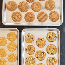 Natural aluminum cookie sheet with patterned baked cookies and raised rim