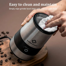 LINKChef coffee grinder with open grinding bowl and hand wiping residue off the lid