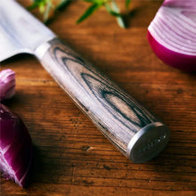 Stainless Damascus knife blade and dark wood handle close-up on wooden cutting board