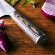 Chef's knife side view with damascus blade and dark wood handle on a board