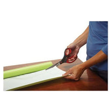 Bent scissors cutting on a work surface; green board and dark handle visible