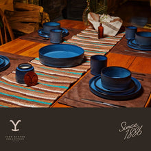 Blue ceramic dinnerware set on dining table with plates, bowls, and stacked cups