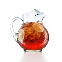 Glass pitcher of iced tea with an orange slice and ice-colored tea surface.
