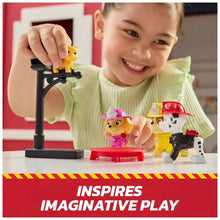 Child playing with Paw Patrol rescue figures on a black stand and red fire platform