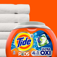 Tide PODS Ultra OXI laundry detergent tub with green pod detail on top of folded towels