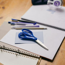 Blue Fiskars pointed scissors on paper with lined notebook